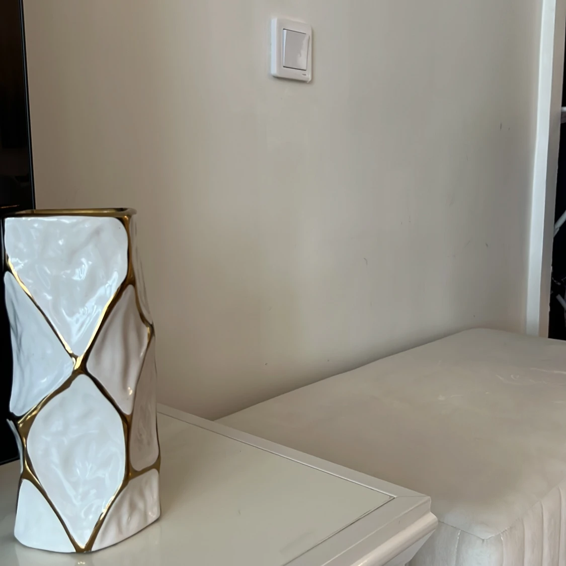 En vit vas med  geometriskt mönster i guld färg