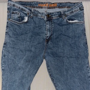 Blå jeans från Hugo Boss - Snygga blå jeans från Hugo Boss med klassisk femficksdesign och bruna kontrastsömmar. Jeansen har en läderpatch med BOSS-logga bak och slitna detaljer vid fickorna. Perfekta för en avslappnad och trendig look. A kop*a