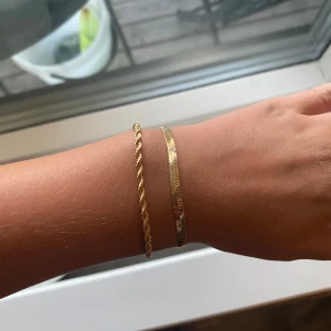 Två guldiga armband i olika kedjor - Säljer två snygga armband i guldig färg. Det ena har en tvinnad kedja och det andra är platt och slätt. Båda har smidiga klolås och passar perfekt att bära tillsammans för en trendig look. Helt nya! Kan köpas var för sig också! Båda två för 79kr och 1 för 45kr! Pris kan diskuteras!
