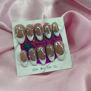SugarDew (S);Medium Almond - Snygga gelé press-on naglar i storlek S: 15 mm, 11,5 mm, 12 mm, 11 mm, 9 mm. Naglarna har en nude bas med superglitter, vit fransk tipp och vita swirl-detaljer. Perfekt för dig som vill ha trendiga naglar snabbt!