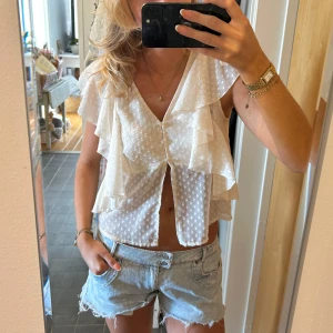 Vit prickig blus med volang - Superfin vit blus med prickigt mönster och volangdetaljer längs axlarna🩷det står L som stl men jag brukar oftast ha S i toppar och den sitter bra🥰