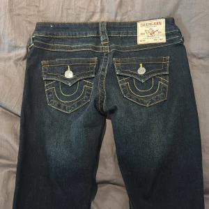 True Religion Joey bootcut jeans mörkblå - Mörkblå jeans från True Religion, modell Joey med låg midja och bootcut. Strl 25. Aldrig använda ute. Testat hemma endast en gång. Jag köpte dem för 1600 kr.