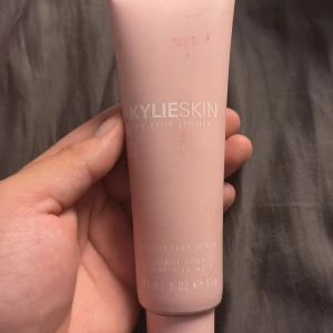 Kylie Skin Walnut Face Scrub - Kylie Skin Walnut Face Scrub i en ljusrosa tub på 85g. Exfolierande ansiktsskrubb med valnöt, perfekt för att fräscha upp huden. Snygg minimalistisk design och smidig att ha med i necessären. Texten på tuben är i vitt och produkten är skapad av Kylie Jenner.