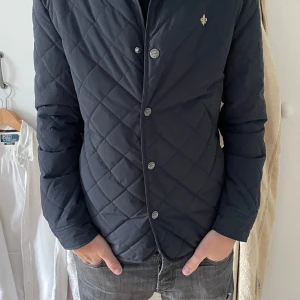 Quiltad unik jacka från Morris - Snygg quiltad svart jacka från Morris med klassisk passform. Den funkar perfekt året runt. Jackan har knappar framtill, diskret logga på bröstet och rutmönstrad yta. Passar till både jeans och chinos.    Nypris: 3599kr. Hör gärna av dog vid frågor eller funderingar! Mvh Melker 