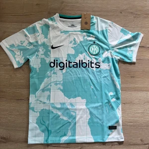 Inter Milan bortatröja 2023/24 Nike - Inter Milans officiella bortatröja 2023/24 från Nike. Tröjan är vit med ljusblå kartmönster över hela ytan, svart Nike-logga och klubbmärke på bröstet. Digitalbits och Lenovo som sponsors. Tillverkad i lätt och ventilerande polyester.