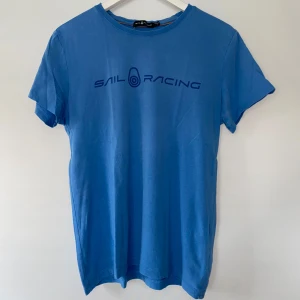 Blå Sail Racing T-shirt  - Säljer en ljusblå sail racing T-shirt. Storlek S i bra skick men håll i nacken som knappt syns. 