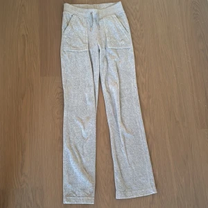 Grå mjukisbyxor Juicy Couture XS - Grå mjukisbyxor från Juicy Couture med raka ben, snörning i midjan och fickor både fram och bak med snygga detaljer. Mjukt bomullsmaterial som är superbekvämt och perfekt för chill dagar. Klassisk Juicy-stil med diskret logga på ena fickan. Köpt för 1000kr och säljer nu för 500 kr. Dessa har använts mindre än 15 gånger.