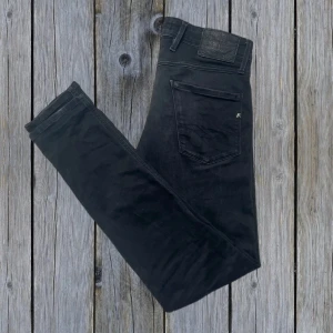 Svarta Replay Anbass jeans - Snygga & stilrena svarta jeans från Replay i slim fit modell Anbass. Ett par eftertraktade jeans som är väldigt trendiga inom grisch-stilen. Slim passform | Storlek: 30/32✅ | Skick: 7,5/10 | Tveka inte att höra av er vid minsta fundering! 😊
