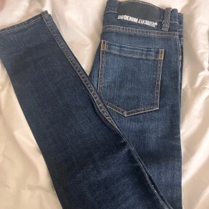 Dr Denim Snap 201 jeans blå 27/32 - Mörkblå jeans från Dr Denim, modell Snap 201. Klassisk femficksdesign med kontrastsömmar och normal passform. Jeansen är raka i modellen och tillverkade i mjukt denimtyg som sitter snyggt på kroppen. 27= midjemått (68-70cm) 32=benlängd (81-82cm) nypris:500kr