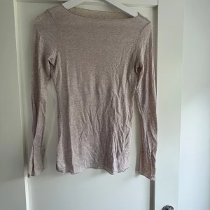 Beige långärmad - En enkel och mjuk långärmad tröja i beige ton. Tröjan har rund halsringning och är figurnära i modellen, perfekt att styla med jeans eller kjol. Materialet känns lätt och stretchigt, vilket gör den skön att bära hela dagen.