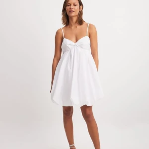 Vit kort klänning med tunna axelband - Supersöt vit kortklänning med tunna axelband och lätt volym i kjolen. Klänningen har en söt twistad detalj vid bysten och en luftig känsla, perfekt för varma dagar. Enkel och stilren design som känns fräsch och modern. Perfekt för sommarens alla tillfällen samt som en studentklänning✨✨✨Ord pris:599 men kan diskuteras. Oanvänd pga hittade en annan klänning, prislappen är kvar.