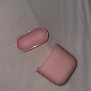 Rosa silikonfodral till AirPods - Säljer ett mjukt och stilrent rosa silikonfodral som passar till AirPods. Fodralet har en enkel design med rundade kanter och öppning för laddning. Perfekt för att skydda dina hörlurar och ge dem en söt look.
