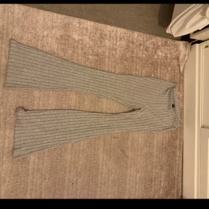 Grå ribbade bootcut byxor - Snygga grå ribbade byxor med bootcut och hög midja. De är stickade i ett mjukt material och har en skön loose passform. Perfekta för en chill och trendig look.