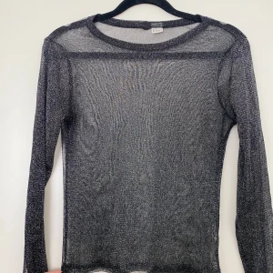 Svart glittrig tröja  - Jättefin glittrig och genomskinlig tröja i storlek xs. Materialet är dock väldigt stretchigt och skulle passa upp till storlek L också.
