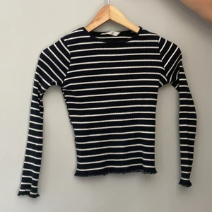 Svartvit randig ribbad långärmad tröja från Mango - Säljer en svart och vit långärmad tröja med smala horisontella ränder. Tröjan är ribbad och har en tight passform med lätt vågiga kanter vid ärmslut och nederkant. 