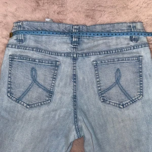 Ljusblå jeans från Rainbow Collection - Säljer ett par ljusblå jeans från Rainbow Collection med snygga detaljer på bakfickorna. Byxorna är ganska raka. Innerbenslängd: 78 cm, midjemått: 38 cm