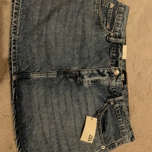 Blå jeanskjol från Lager 157, storlek L - Helt oanvänd blå jeanskjol från Lager 157, lapparna sitter fortfarande kvar. Normal passform, låg midja och kort längd. Knäppning framtill med knappar. Nypris 150kr. Säljer den då den tyvärr är för stor för mig.
