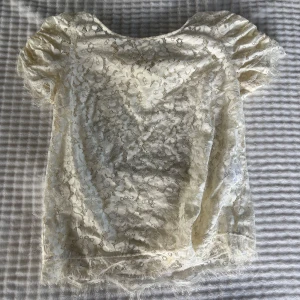 Vit spetsblus från Stockh lm - Superfin vit blus från Stockh lm i genombruten spets med blommigt mönster. Korta puffärmar med rynk och fransiga kanter ger en romantisk vibe. Perfekt att styla med jeans eller kjol för en cool look.