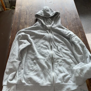 Ljusgrå hoodie med dragkedja Yourturn - Säljer en ljusgrå hoodie från Yourturn med hel dragkedja framtill, huva med snörning och två stora fickor. Tröjan är i mjuk bomullsmix och har långa ärmar. Perfekt för chill dagar eller när du vill ha en enkel och clean look.