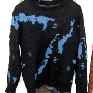 Svart stickad tröja med blå detaljer - svart stickad tröja med blå abstrakta mönster och detaljer.