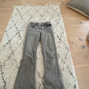 Grå bootcut jeans från Gina Tricot - Snygga grå bootcut jeans från Gina Tricot i storlek 146. De har en klassisk femficksdesign och en knapp med dragkedja i gylfen. Perfekta för en stilren look. Justerbar resår i midjan💖
