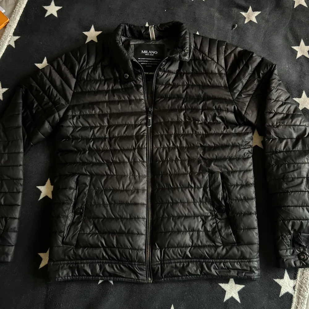 Säljer en svart quiltad jacka från Milano med dragkedja framtill. Jackan har en modern passform och är perfekt för kyligare dagar. Den är designad med högkvalitativt material och har praktiska fickor med dragkedja. Det finns ett antal defekter därför är priset så lågt. Finns på båda fickor och vid ena armen. Men defekten på armen syns inte. Ifall du har några frågor så är det bara att höra av dig!!! . Takit.