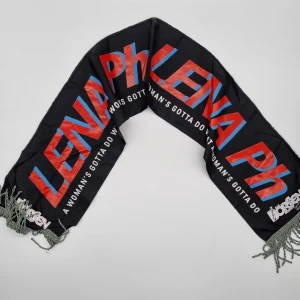 Lena (Roxette) Philipsson turnéhalsduk tour scarf halsduk med text - svart halsduk med 'LENA Ph' i rött och blått. Har fransar i ändarna och texten 'A woman's gotta do what a woman's gotta do'. Perfekt för att sticka ut i mängden & samlaren