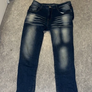 Mörkblå jeans med slitningar - Snygga mörkblå jeans med coola slitningar på låren. De har en klassisk femficksdesign och knappgylf. Perfekta för en avslappnad stil.