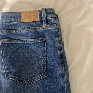 blå low waist bootcut jeans från gina young - Snygga blå jeans från Gina Tricot med klassisk femficksdesign och dragkedja. Jeansen har en lätt tvättad look och är perfekta för en avslappnad stil. De har en bootcut passform och är tillverkade i ett bekvämt denimtyg. endast lite slitna i botten.