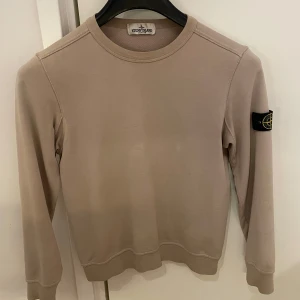 Beige sweatshirt från Stone Island - Snygg beige sweatshirt från Stone Island i storlek 152, bra skick! Tröjan är köpt på NK i Stockholm. Jag säljer denna tröja då jag har växt ur den, har ni frågor angående pris eller annat är det bara att skriva:)