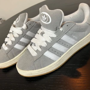 Grå Adidas Campus sneakers - Mycket bra skick, väldigt få tecken på användning. Strl 39 1/3. (Har råkat snöra de lite olika på bilden)
