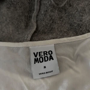 Vit långärmad klänning från Vero Moda - Säljer en stilren vit långärmad klänning från Vero Moda. Klänningen har en rund halsringning och knappar på ärmarna för en extra detalj. Perfekt för en avslappnad look.