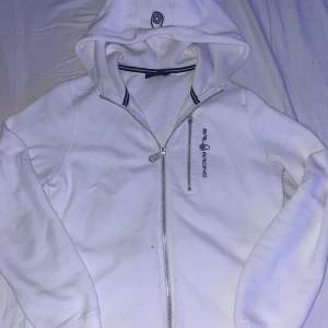 Vit huvtröja från Sail Racing - Säljer en vit huvtröja från Sail Racing för jag vuxit ur den. Väldigt fint skick knappt använd,storleken är 160-165 vilket motsvar xs-s. hör av er för mer info!