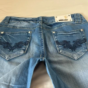 Low jeans - Jättesnygga vintage jeans med broderade fickor!! Jeansen är väldigt lågmidjade samt bootcut😍😍😍toppen skick, inga defekter!! Köptes för 1000 kronor och svårt att få tag i nu