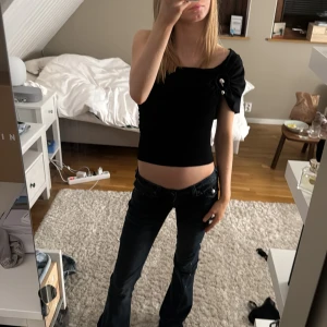 Svart offshoulder topp  - Snygg svart topp som antigen går att ha som one-shoulder eller off shoulder. Har en gulddetalj vid axeln. Aldrig använd med lappen är av