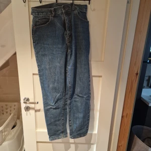 Blå jeans från Dr. Denim - Säljer ett par klassiska blå jeans från Dr. Denim. De är högmidjade med en straight passform och har en dragkedja och knapp framtill. Tyvärr har två av bältesöglorna gått sönder.