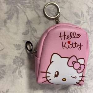  Hello Kitty Mini Ryggsäck / Myntbörs / Nyckelfall  - Söt liten rosa plånbok med Hello Kitty-motiv. Perfekt för att hålla dina småsaker organiserade. Den har en dragkedja och en nyckelring för enkel fastsättning på väskan eller nyckelknippan.  79kr/st , helt ny 
