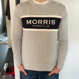 Grå tröja från Morris - Säljer en stilren grå tröja från Morris med texten 'Morris Rowing Club' i svart och vitt på bröstet. Tröjan har långa ärmar och ribbade muddar vid ärmslut och nederkant. Perfekt för en avslappnad och trendig look.