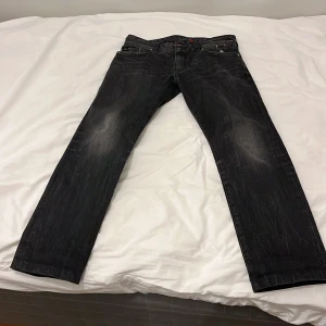 Svarta jeansbyxor från Tribeca - Snygga svarta jeansbyxor från Tribeca med en cool sliten look. De har en klassisk femficksdesign och en läderpatch med logotyp baktill. Perfekta för en avslappnad stil.