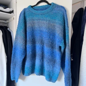 Blå stickad tröja - Säljer en mysig stickad tröja som har en melerad design i olika blå nyanser och är perfekt för kyligare dagar. Den har långa ärmar och en rund halsringning. Passar bra för både avslappnade och stilrena outfits. Aldrig använd. Stor i storleken!! Önskar du exakta mått? Tveka inte att höra av dig!