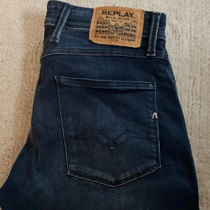Mörkblå jeans från Replay - Snygga mörkblå jeans från Replay i modellen Anbass. Dessa jeans har en slim fit passform och är tillverkade i ett klassiskt denimtyg. Perfekta för en stilren look med en modern touch.