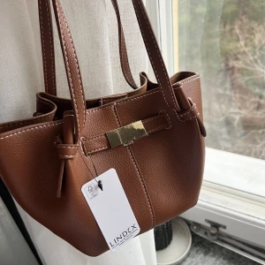 Brun väska Lindex - Superfin och trendig väska från Lindex! Helt slutsåld och helt ny med prislappen kvar 💕