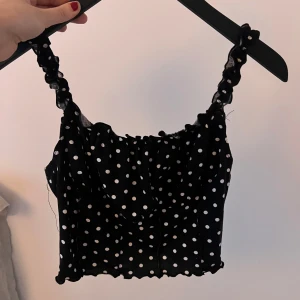 Svart prickig linnetopp - Säljer en söt svart linnetopp med vita prickar och volangdetaljer. Från shein.