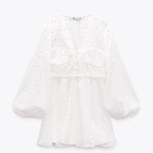 Vit klänning från Zara - Säljer en söt vit klänning från Zara med broderade detaljer och knytning framtill. Perfekt till studenten!