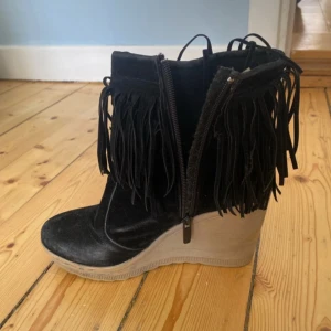 Svarta boots med kilklack och fransar - Snygga svarta boots i mocka med kilklack och fransdetaljer. De har en dragkedja på sidan för enkel på- och avtagning. Perfekta för en utekväll med tjejerna❤️ l