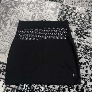 Svart kjol med nitar från ONLY - Snygg svart kortkjol från ONLY med nitar framtill och dragkedja bak. Perfekt för en cool och trendig look. Kjolen har en tight passform som framhäver figuren.