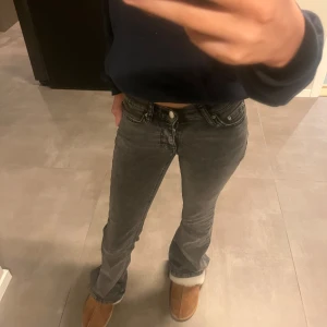 Grå jeans med bootcut - Snygga grå jeans med bootcut-stil och låg midja. Perfekta för en avslappnad look. De har klassisk femficksdesign och knappar framtill.
