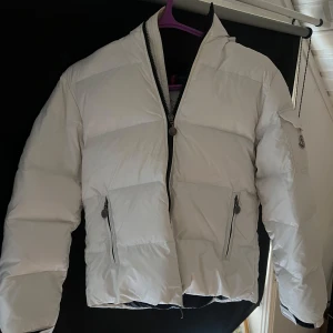 Vit dunjacka från Moncler - Vit dunjacka från märket Moncler skick 9/10 storlek 152cm (12y modellen heter Bazille och är riktigt stilren. Perfekt att ha nu till våren. Hör av er om ni har några frågor eller funderingar 