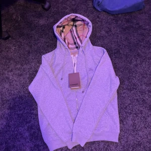 Grå Burberry Hoodie - 📊Färg : Grå med mönstrigt stil på Luvan!  📐Storlek : M  👕Material : 100% Bomull  ⌨️Skriv gärna om det finns frågor! Fraktar samma dag! 