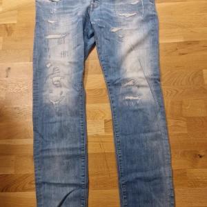 Blå slitna jeans G-Star 34/32 - Säljer ett par blå jeans med slitningar och en cool, avslappnad look. De har en klassisk femficksdesign och en ljus tvätt som ger en vintage känsla. Perfekta för en casual stil.